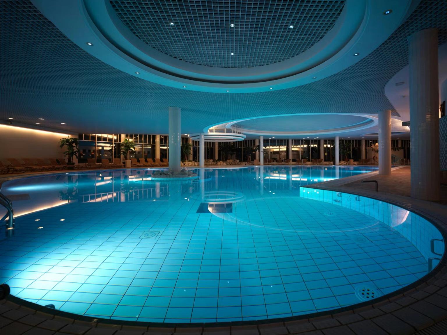 En stor, moderne indendørs swimmingpool med blåbelyst vand.