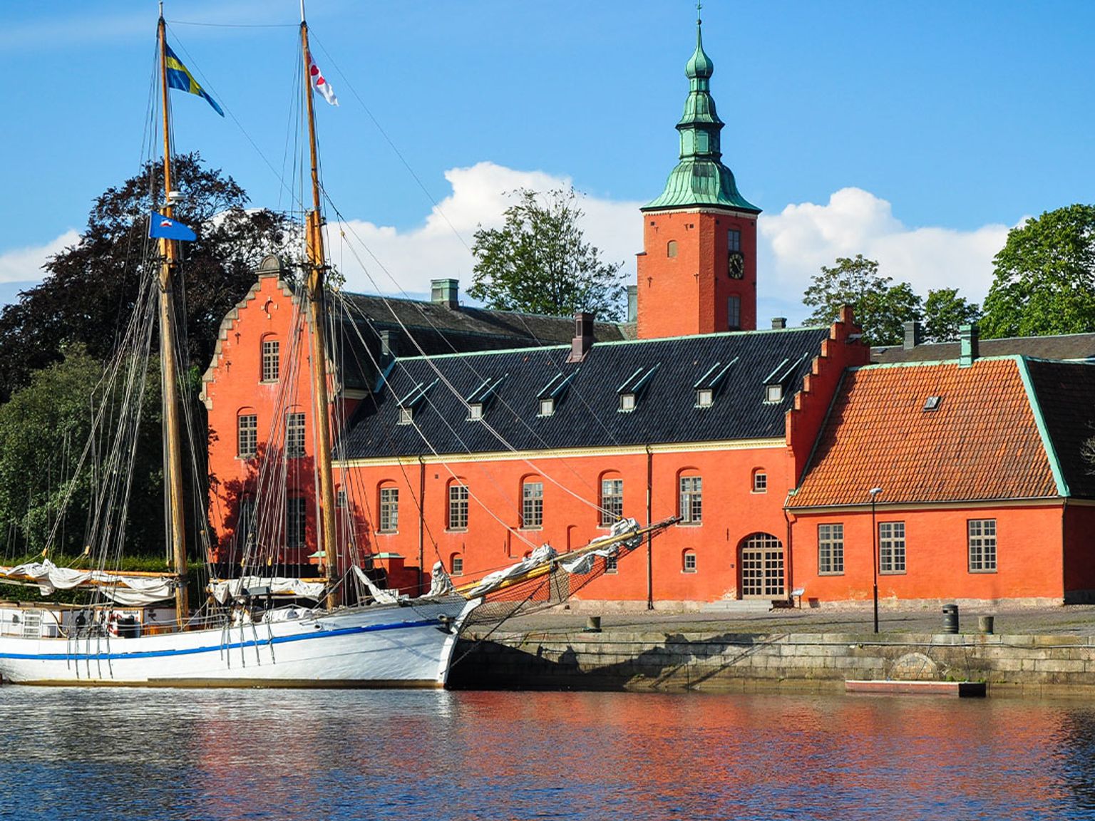 en sejlbåd er docket foran en stor rød bygning