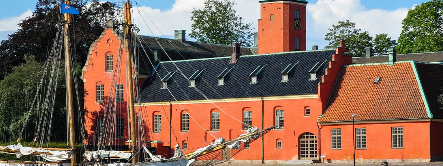 en sejlbåd er docket foran en stor rød bygning