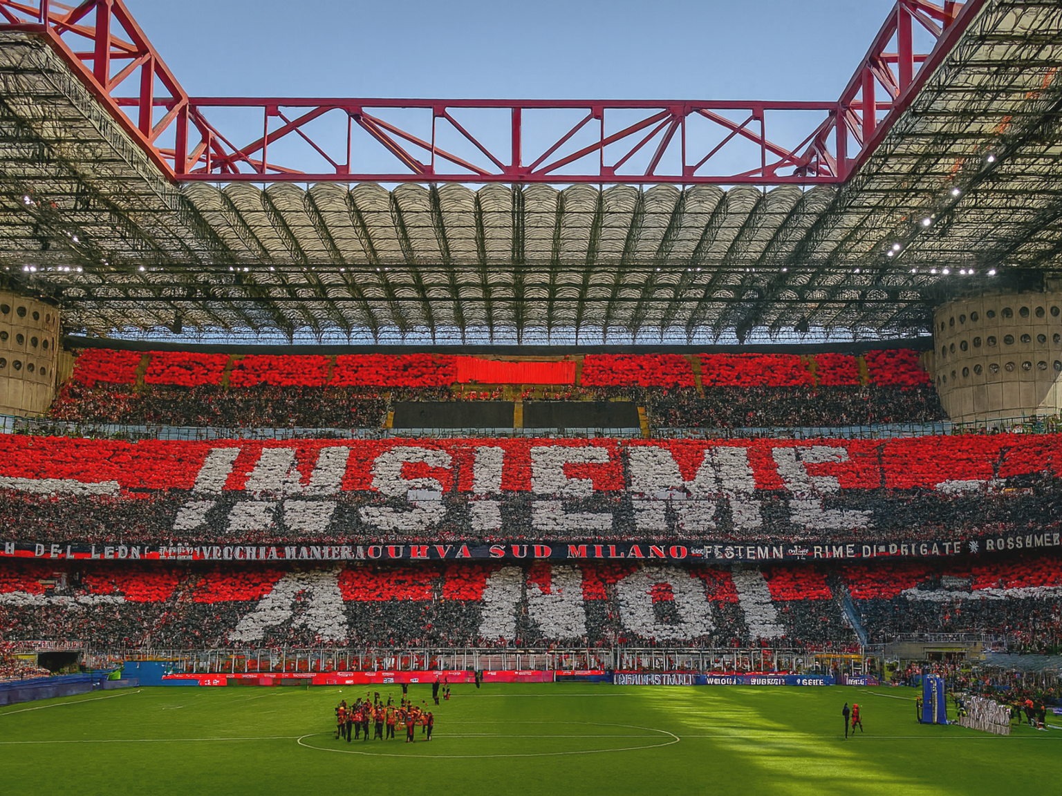A stadium filled with fans holding red, black, and white cards to spell "INSIEME" and other messages, with a football team on the green pitch.