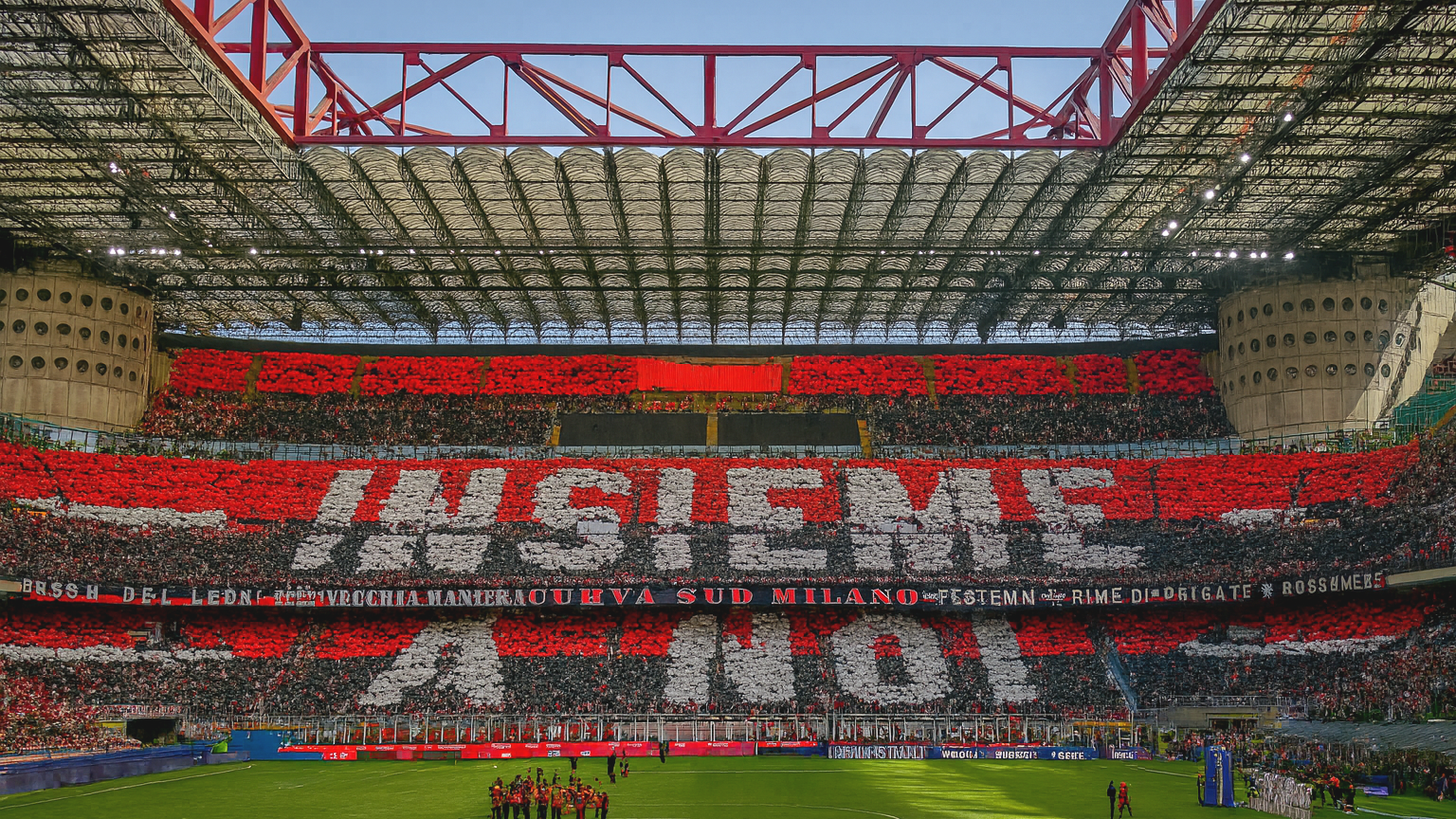 Ein Stadion gefüllt mit Fans, die rote, schwarze und weiße Karten halten, um "INSIEME" und andere Nachrichten zu buchstabieren, mit einer Fußballmannschaft auf dem grünen Spielfeld.