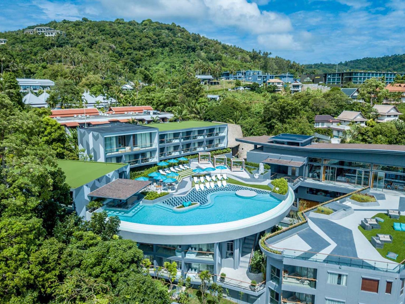 an aerial view of a large swimming pool surrounded by buildings and trees