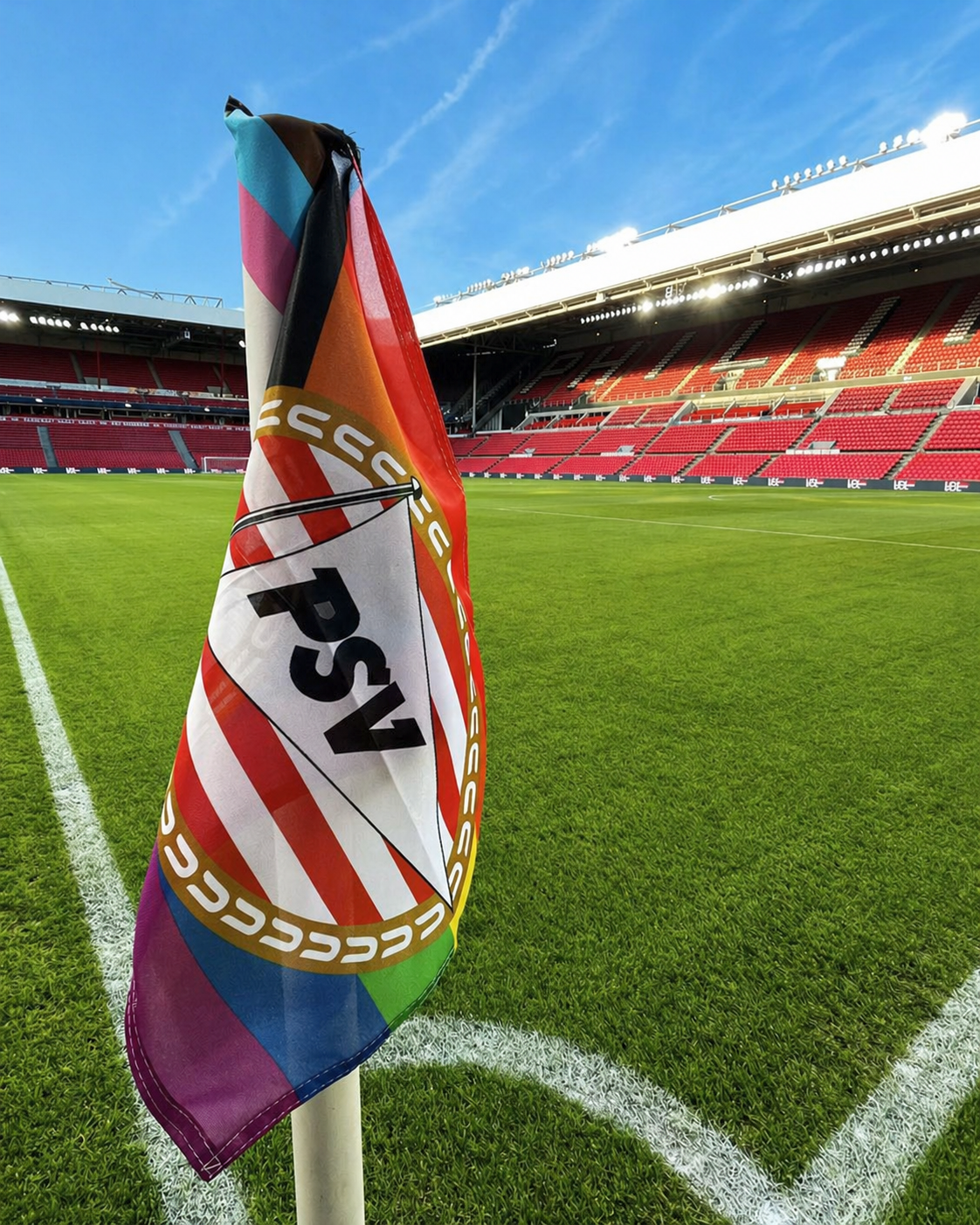Zwei große Fahnen, eine mit PSV-Branding und eine andere mit einem Bulldoggen-Design, wehen über einer Stadionmenge mit erhobenen Fäusten.