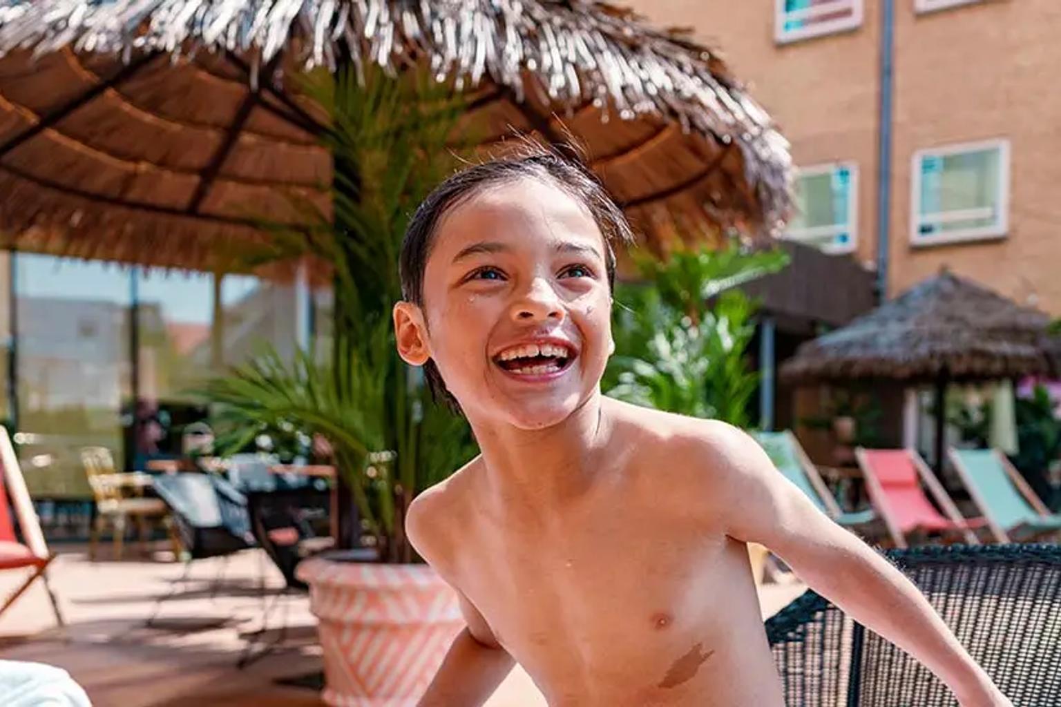 en skjortlös ung pojke står bredvid en swimmingpool.