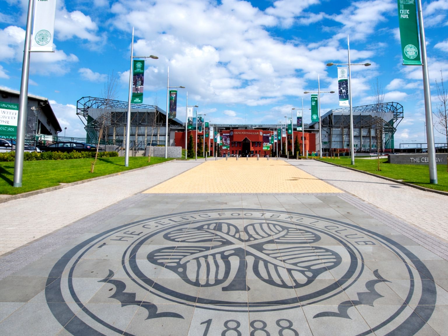 Celtic Football Club-emblem på en stenlagd gångväg som leder till Celtic Park-stadion.