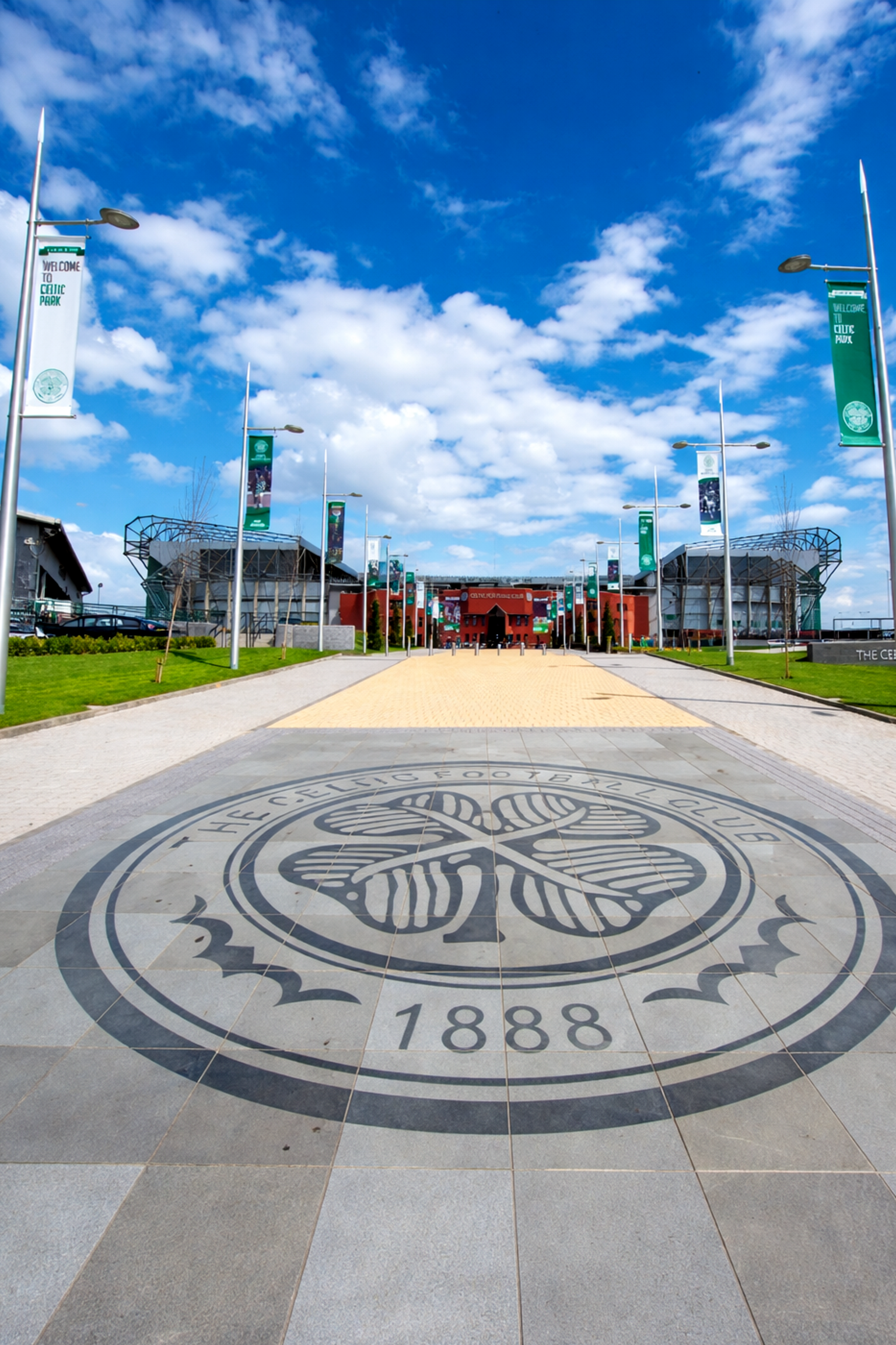 Celtic Football Club-emblem på en stenlagd gångväg som leder till Celtic Park-stadion.