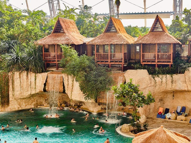 en gruppe mennesker svømmer i en pool ved siden af et vandfald.