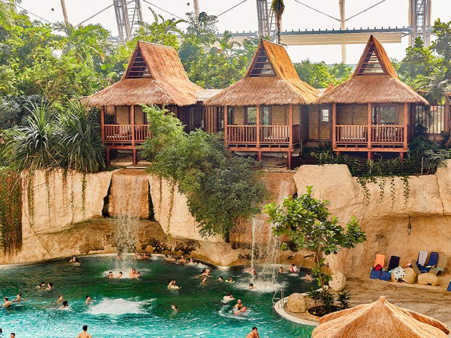 een groep mensen zwemt in een zwembad naast een waterval.