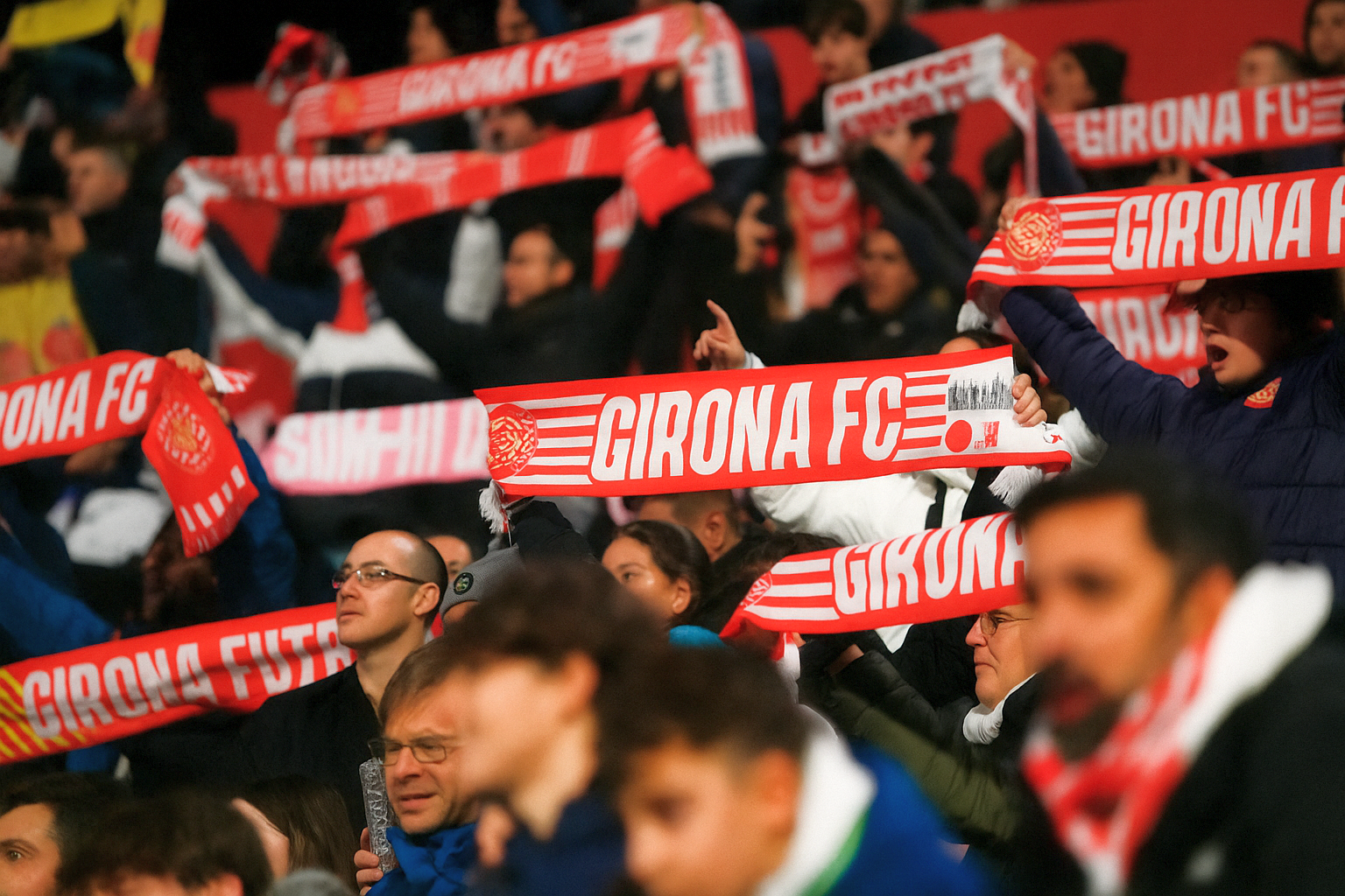 Fanit pitävät ylhäällä punaisia ja valkoisia Girona FC -huiveja.