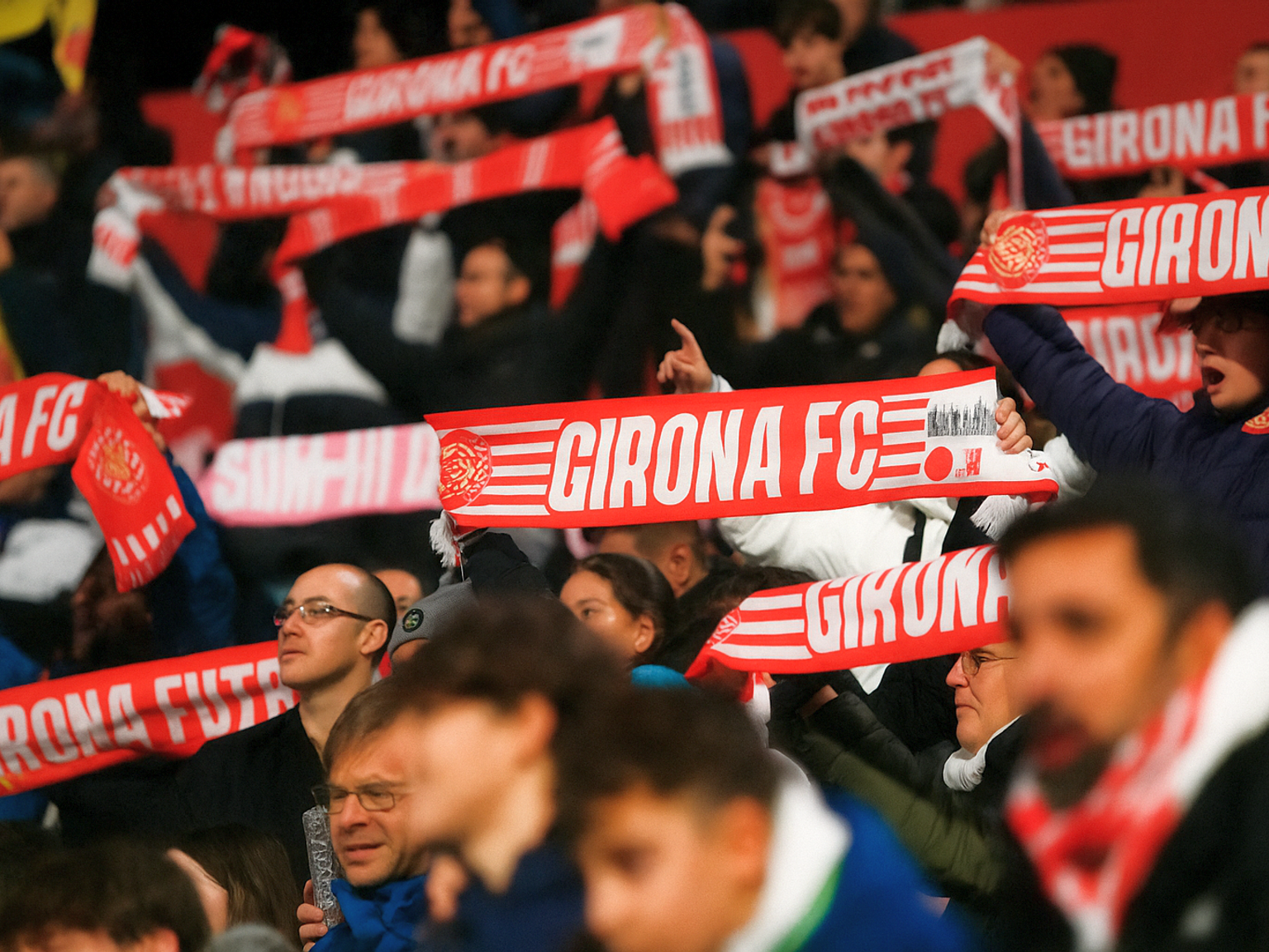 Fani trzymają czerwono-białe szaliki Girona FC.