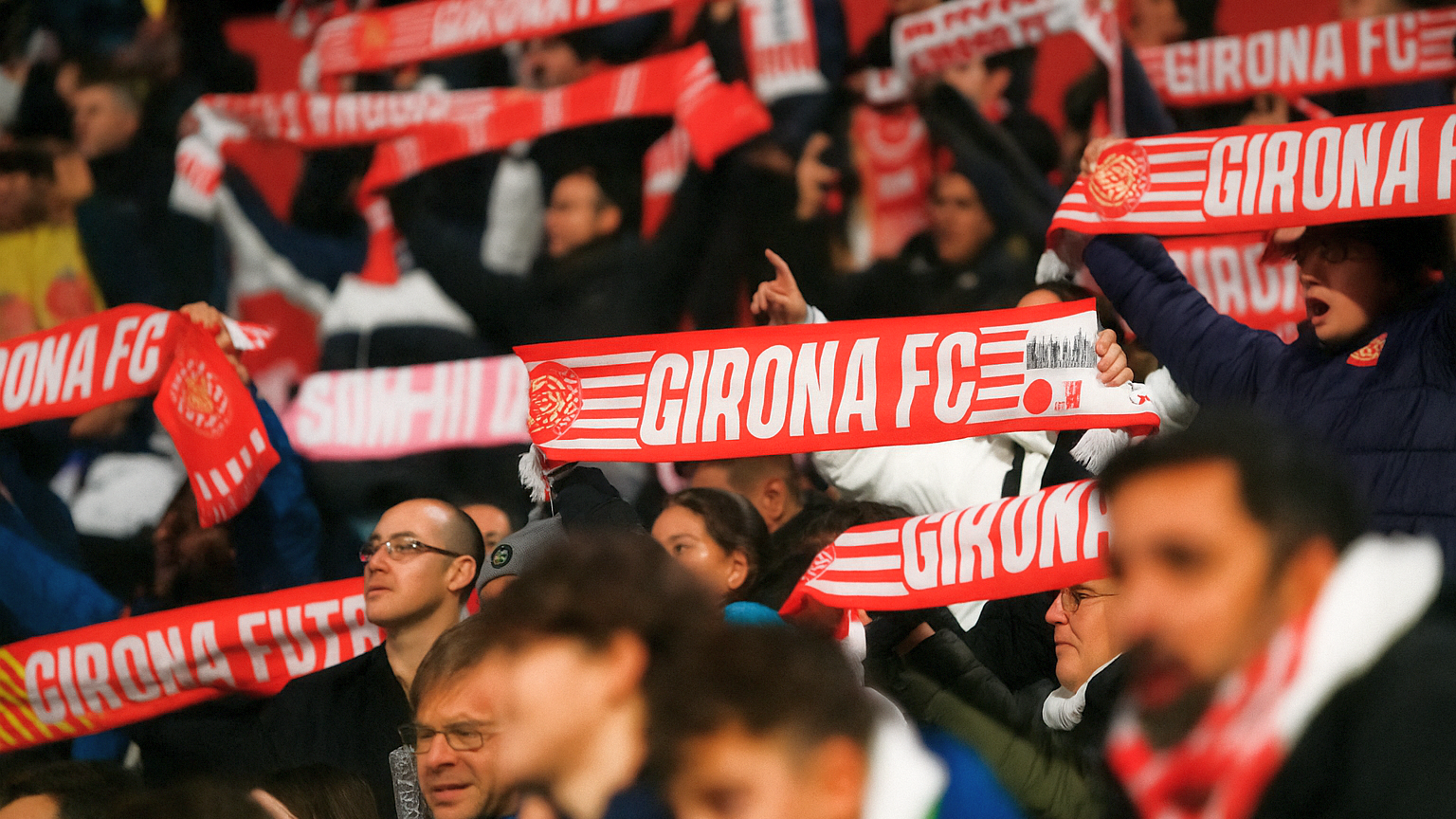 Fanit pitävät ylhäällä punaisia ja valkoisia Girona FC -huiveja.