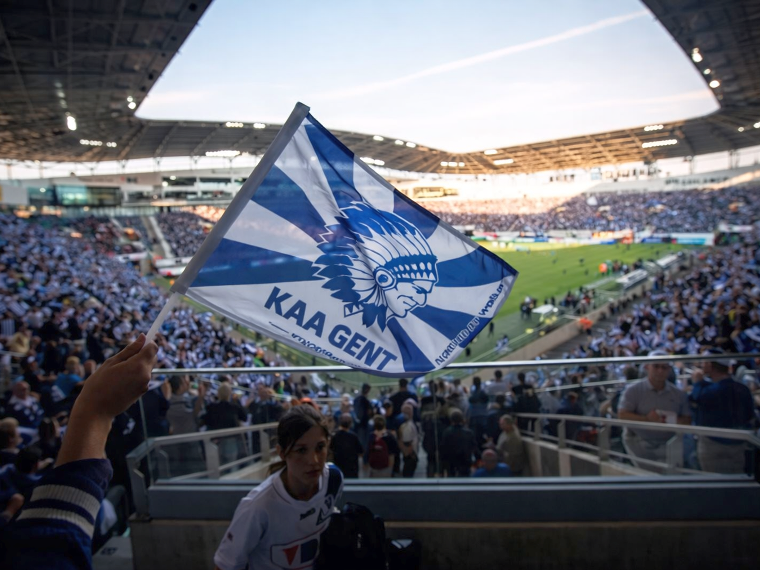 Eine KAA-Gent-Flagge mit einem Logo eines indianischen Häuptlings weht in einem vollen Fußballstadion.