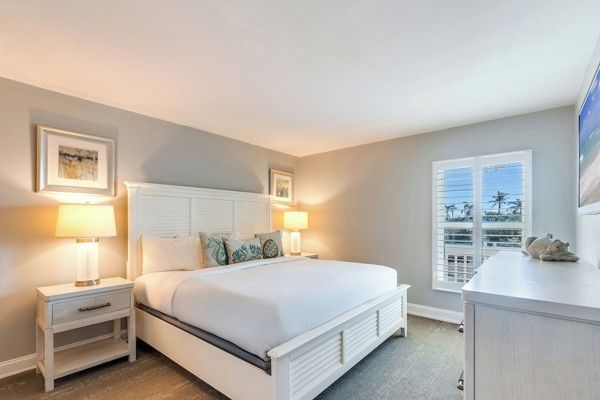 et soverom med en king size seng, kommode, nattbord og vindu.