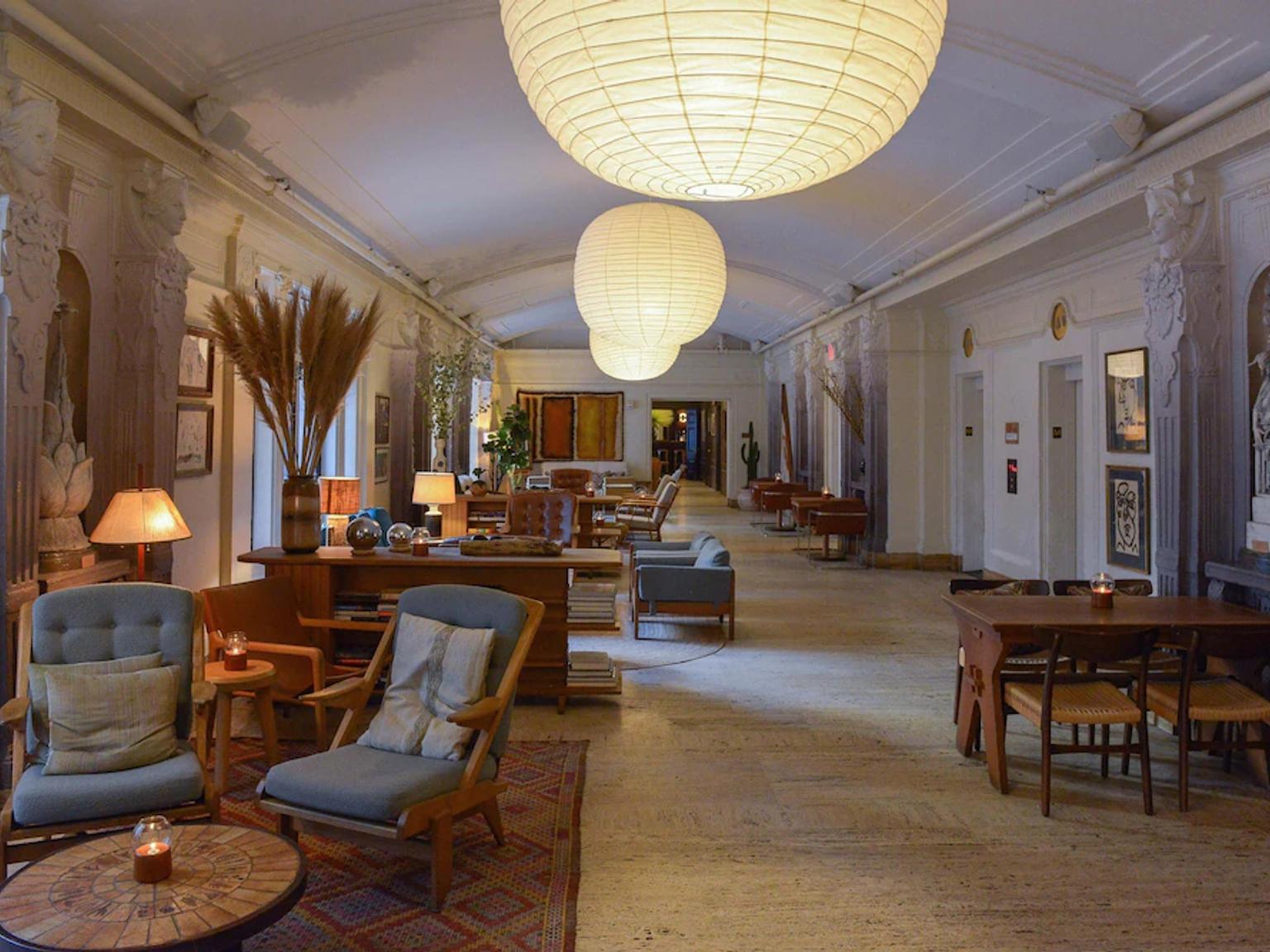 en lång korridor med stolar, bord och lyktor hängande från taket