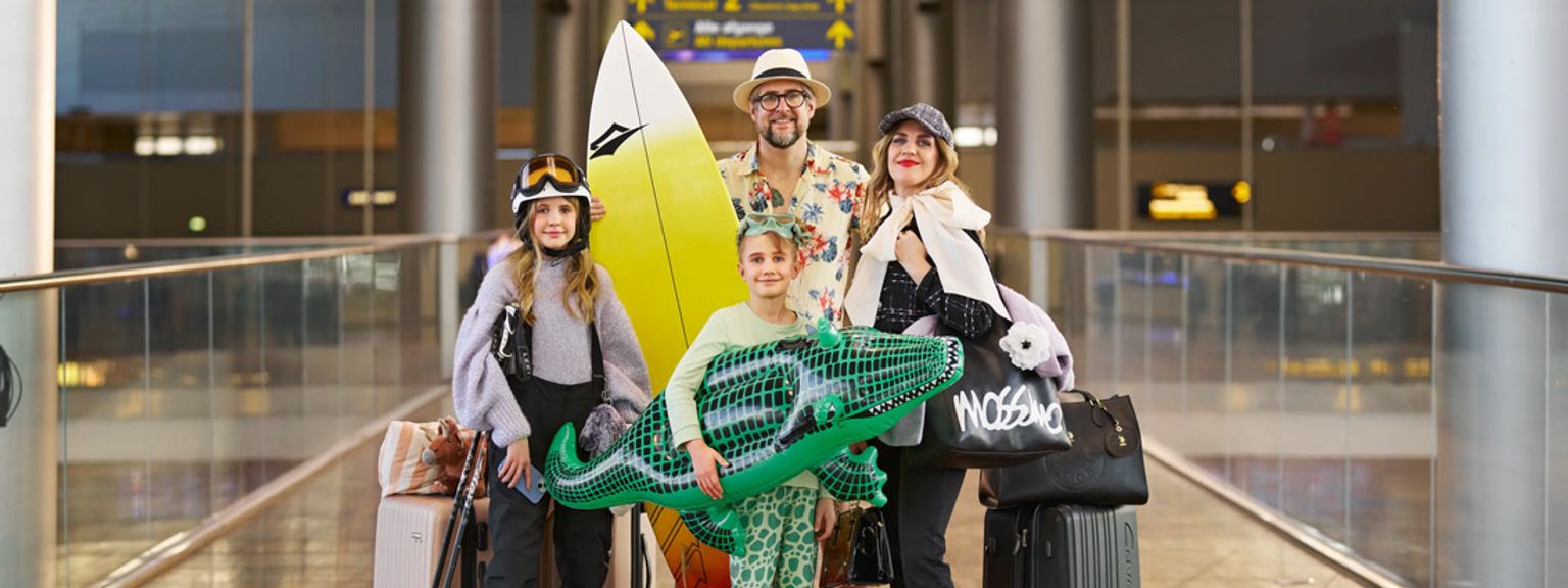 en familie står på en flyplass med bagasje og et surfebrett