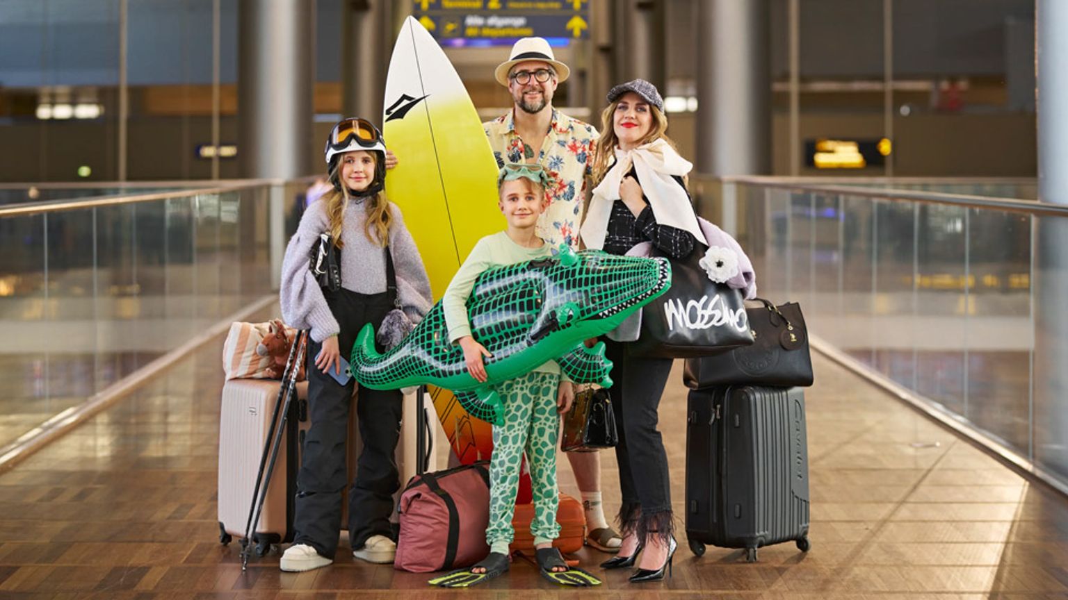 en familie står på en flyplass med bagasje og et surfebrett