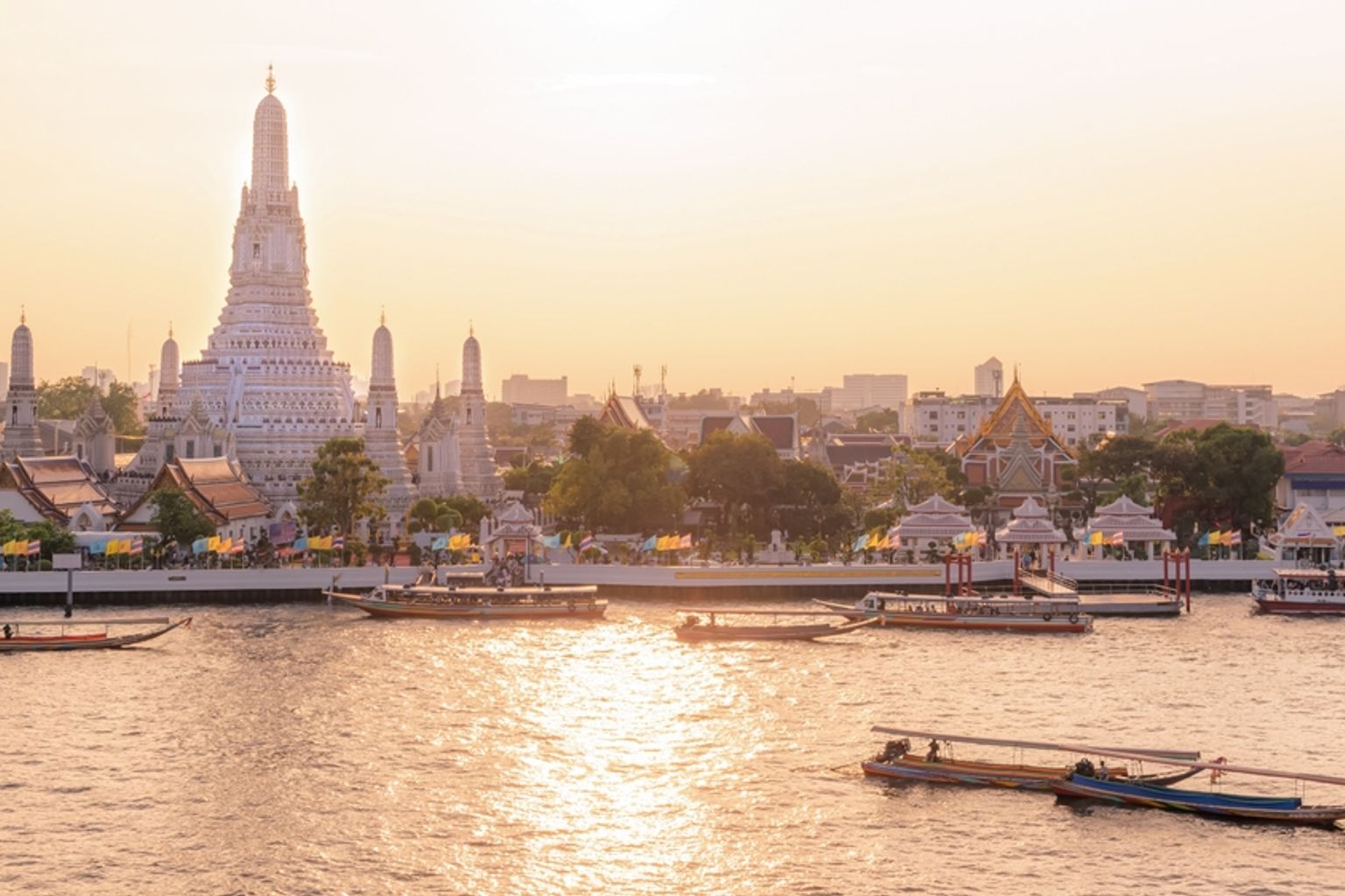 Wat Arun-templet og både på Chao Phraya-floden ved solnedgang. Bangkok