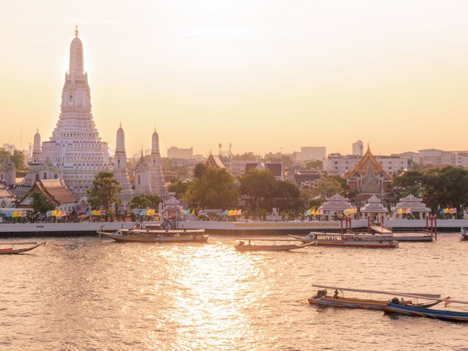 Wat Arun-templet og både på Chao Phraya-floden ved solnedgang. Bangkok