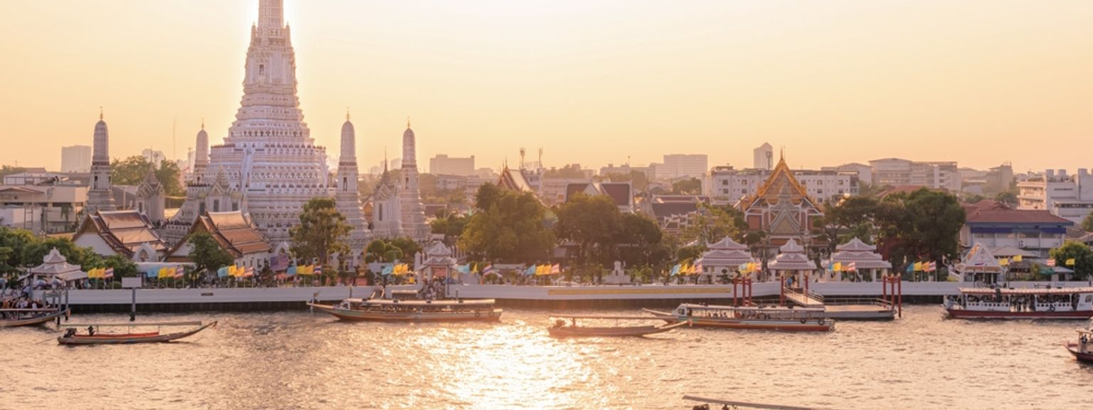 Wat Arun-templet och båtar på Chao Phraya-floden vid solnedgången. Bangkok