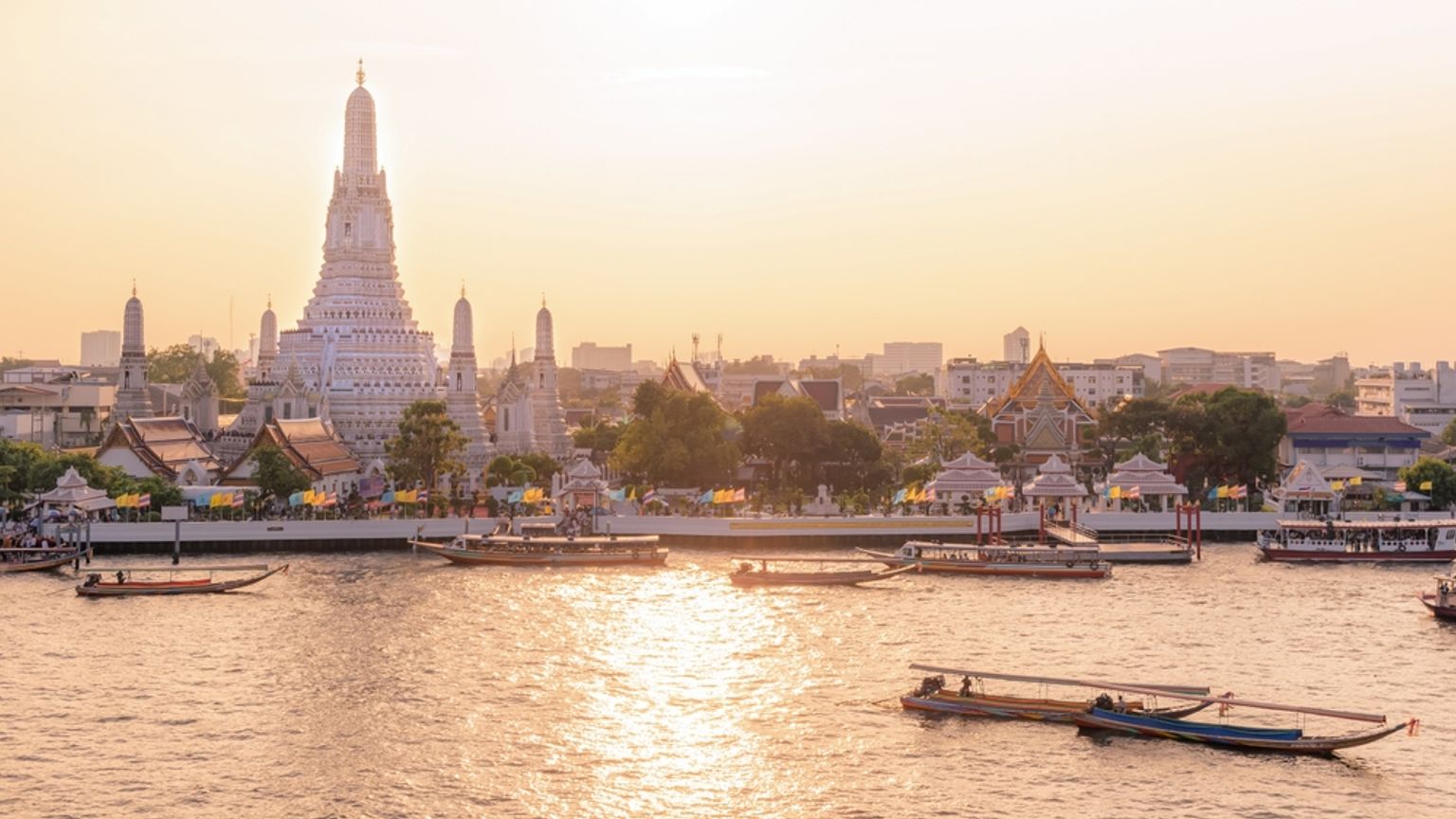 Wat Arun-templet og både på Chao Phraya-floden ved solnedgang. Bangkok