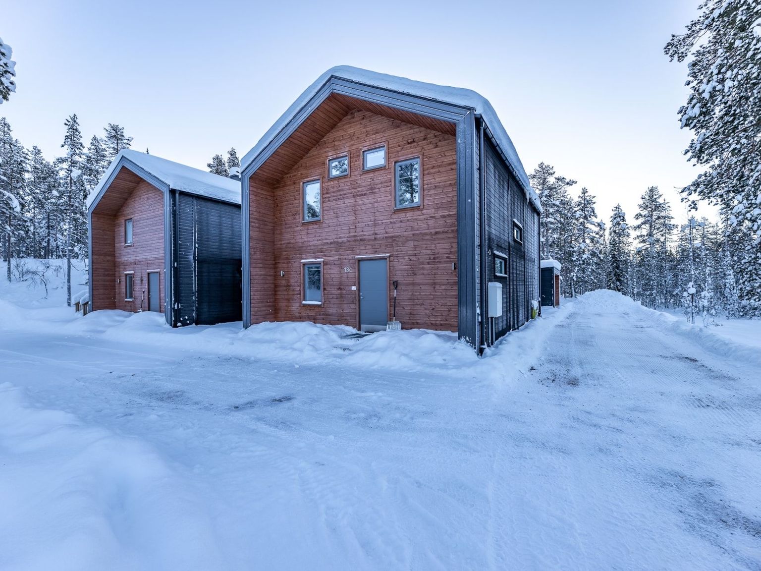 a large wooden house is surrounded by snow and trees.