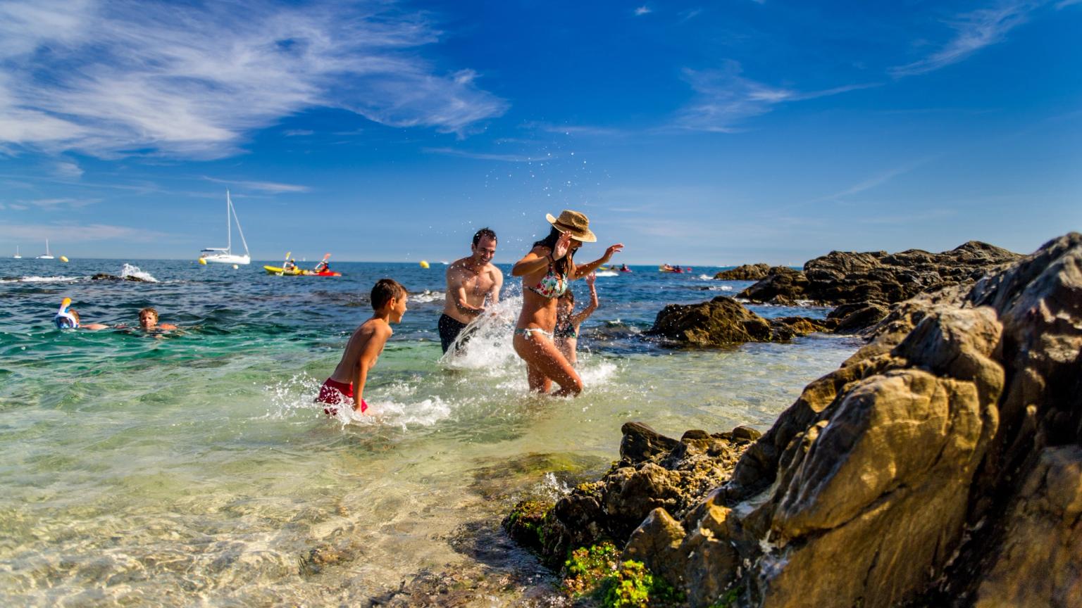 en familie leker i havet på en steinete strand.