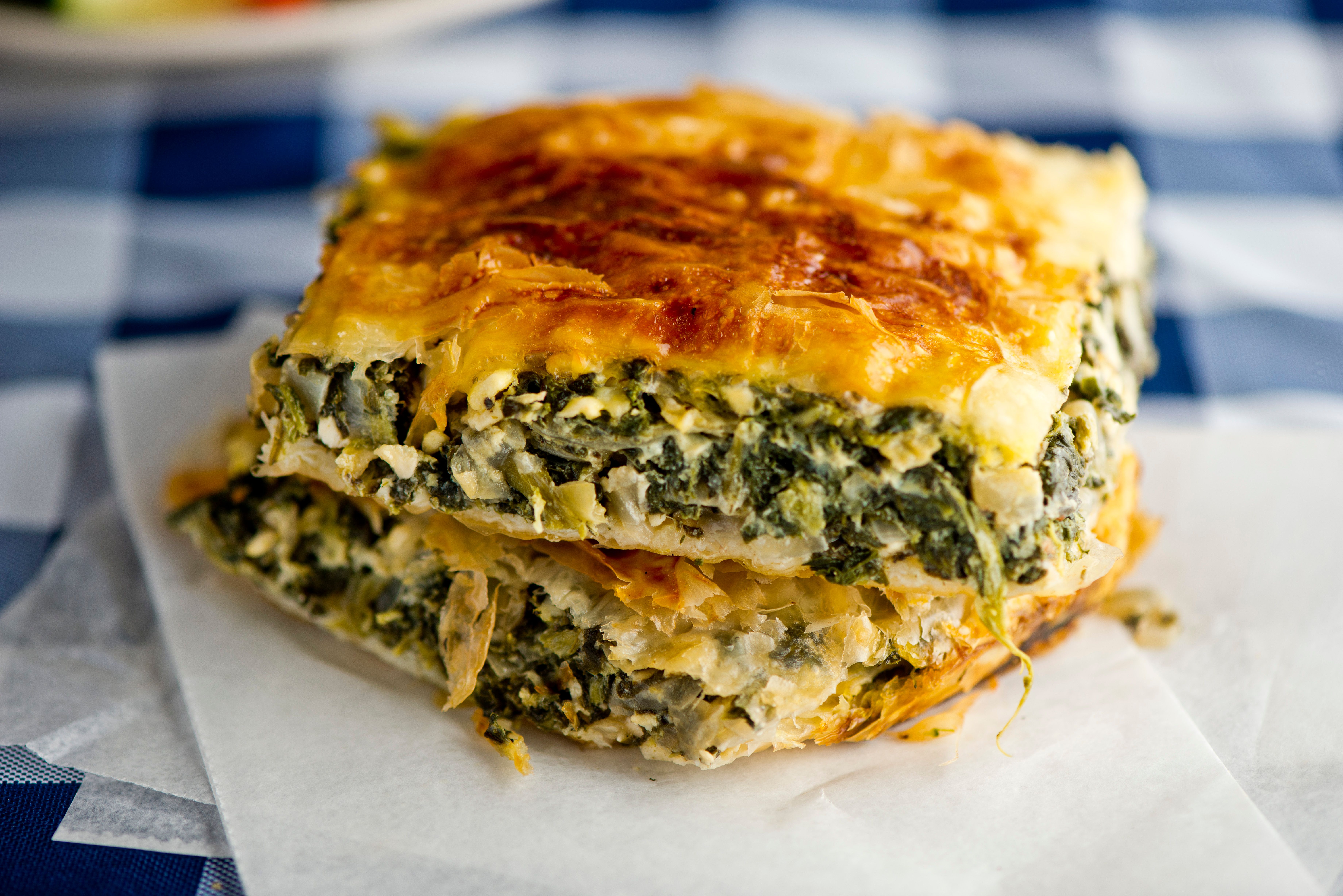 two slices of spinach pie are stacked on top of each other on a napkin on a table