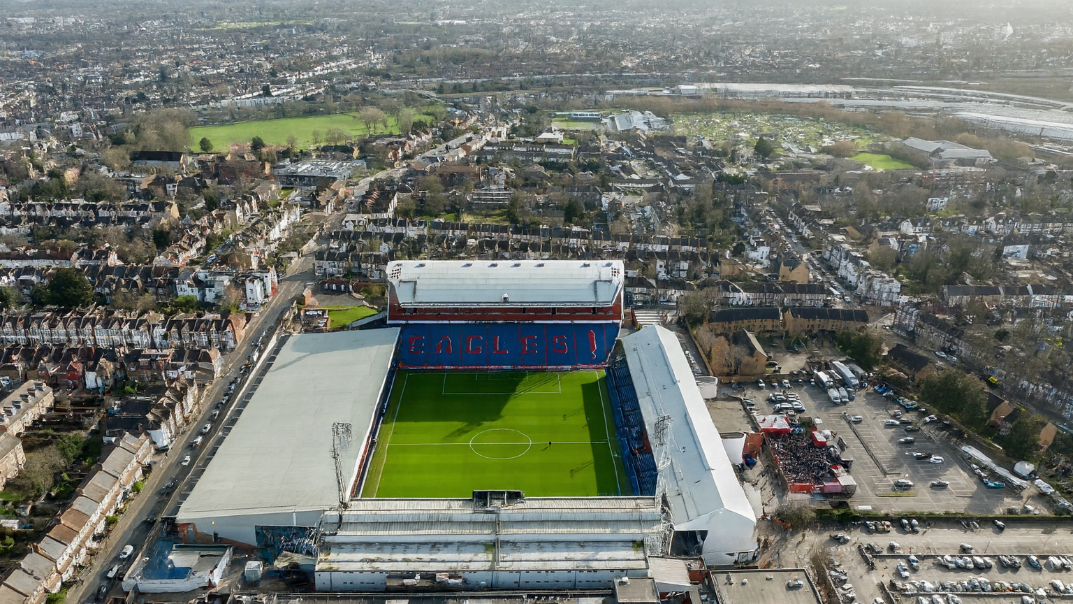 Aerial view of Selhurst Park football stadium displaying "EAGLES" on the stands, surrounded by a dense residential area.
