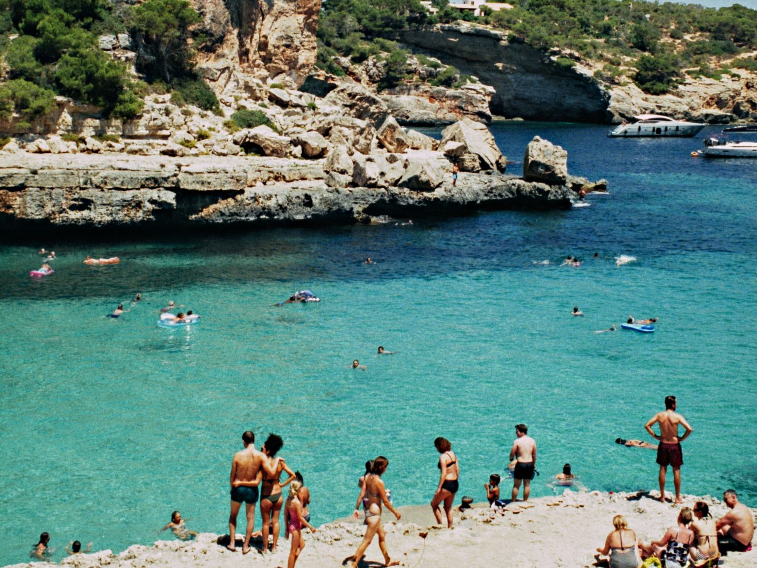 en grupp människor står på en strand nära en vattenmassa