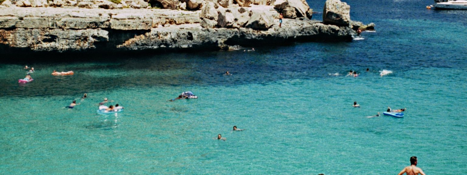 en grupp mÀnniskor stÄr pÄ en strand nÀra en vattenmassa
