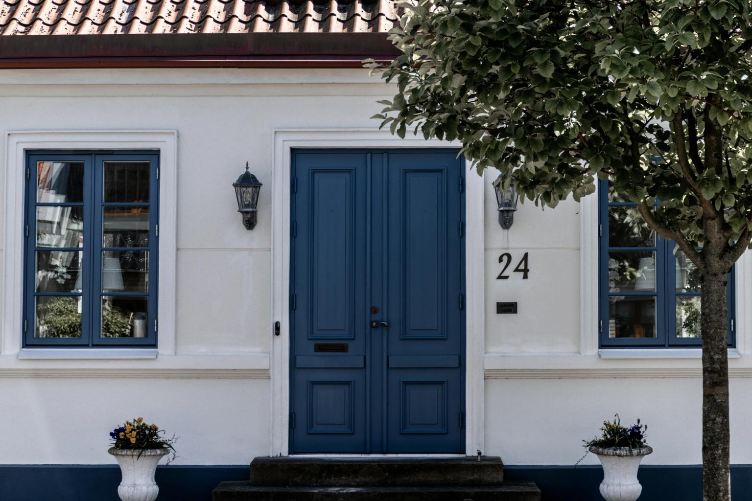 biały dom z niebieskimi drzwiami i numerem 24 na nim