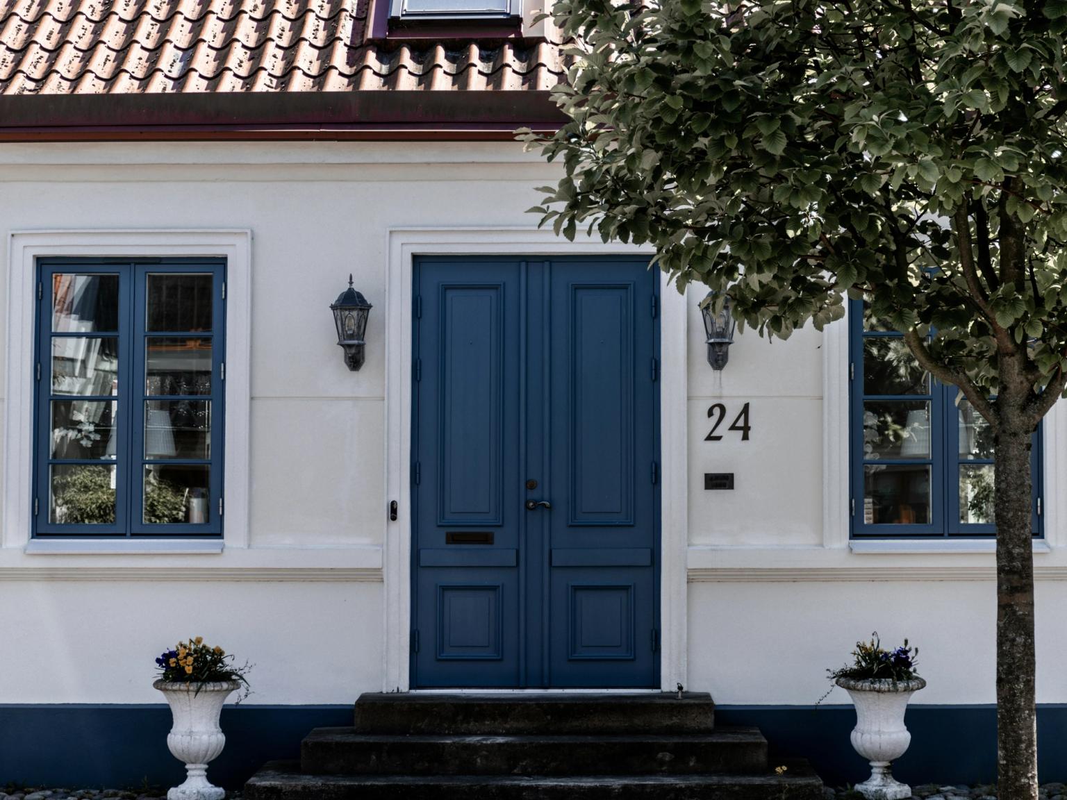 biały dom z niebieskimi drzwiami i numerem 24 na nim