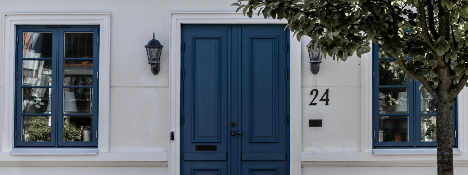 biały dom z niebieskimi drzwiami i numerem 24 na nim