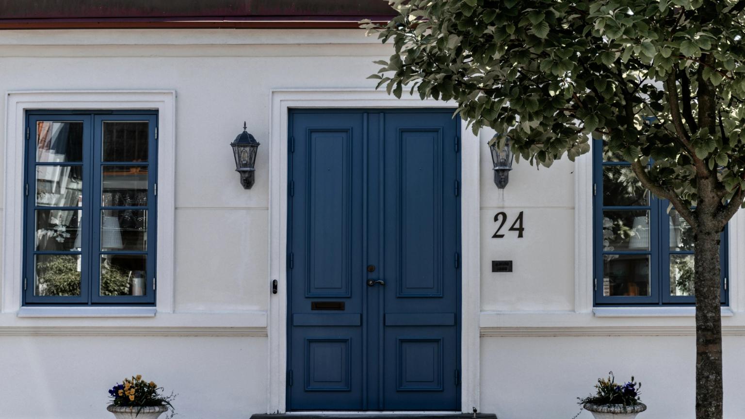 biały dom z niebieskimi drzwiami i numerem 24 na nim