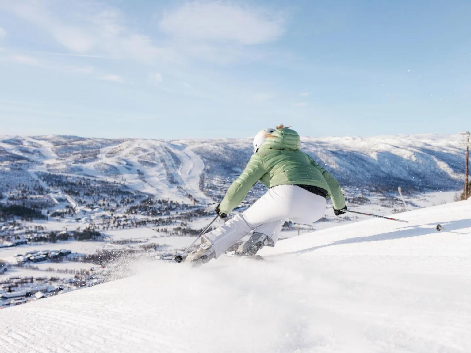 en kvinna åker skidor nerför en snötäckt sluttning.