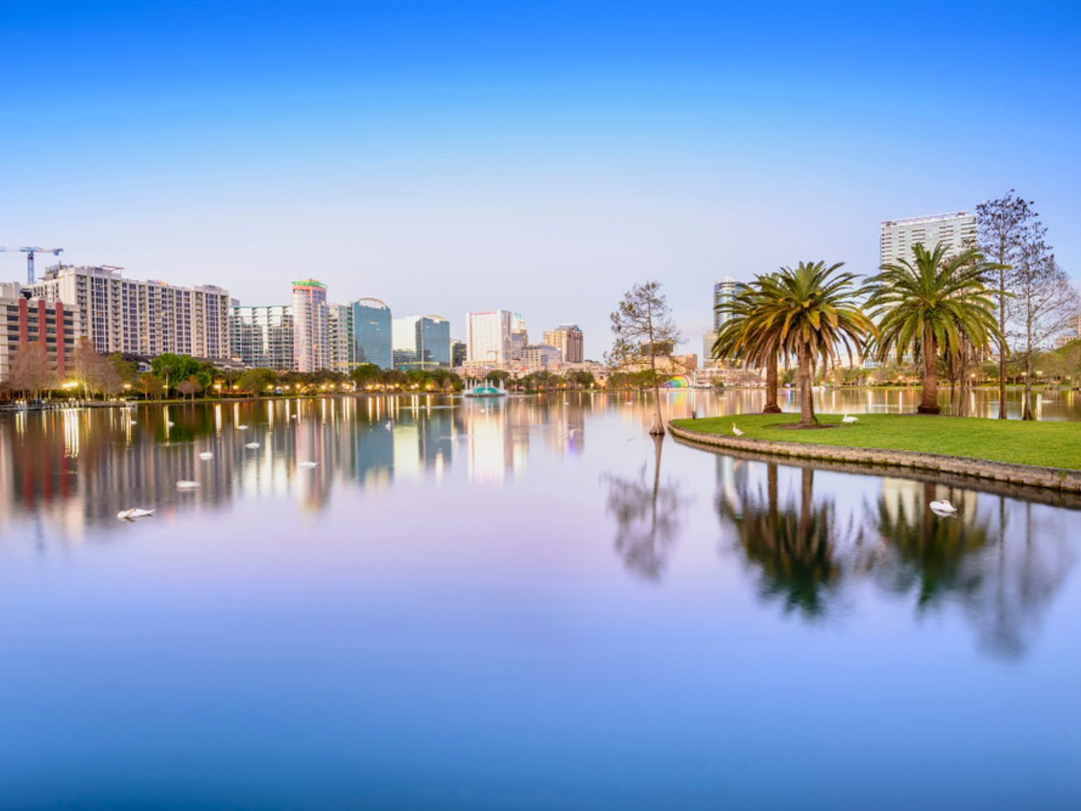Byens skyline, der spejler sig i en sø med palmer. Orlando, Florida