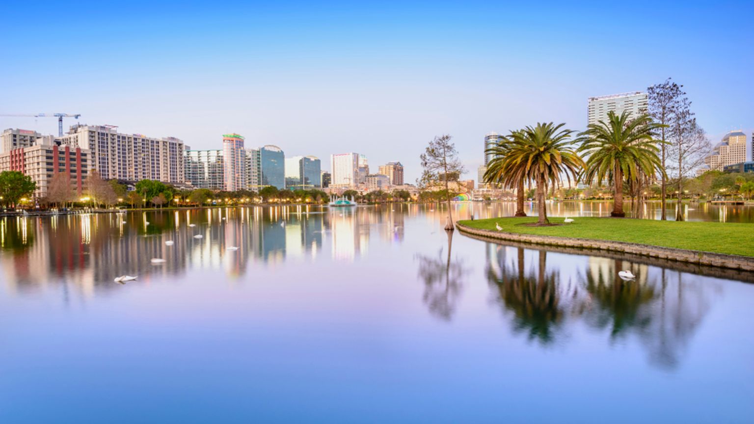 Byens skyline, der spejler sig i en sø med palmer. Orlando, Florida