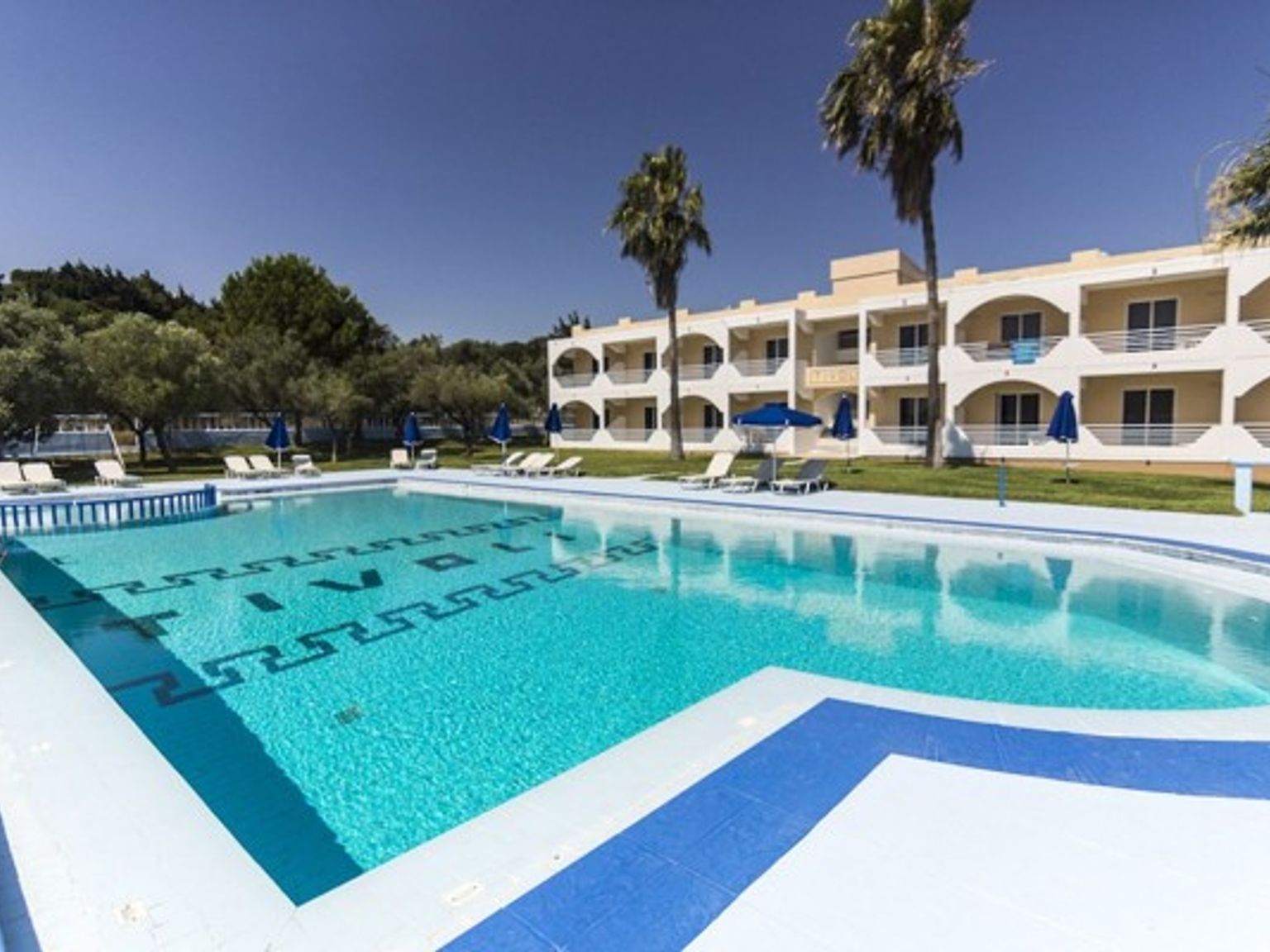 en stor simbassäng framför ett hotell med palmer och stolar