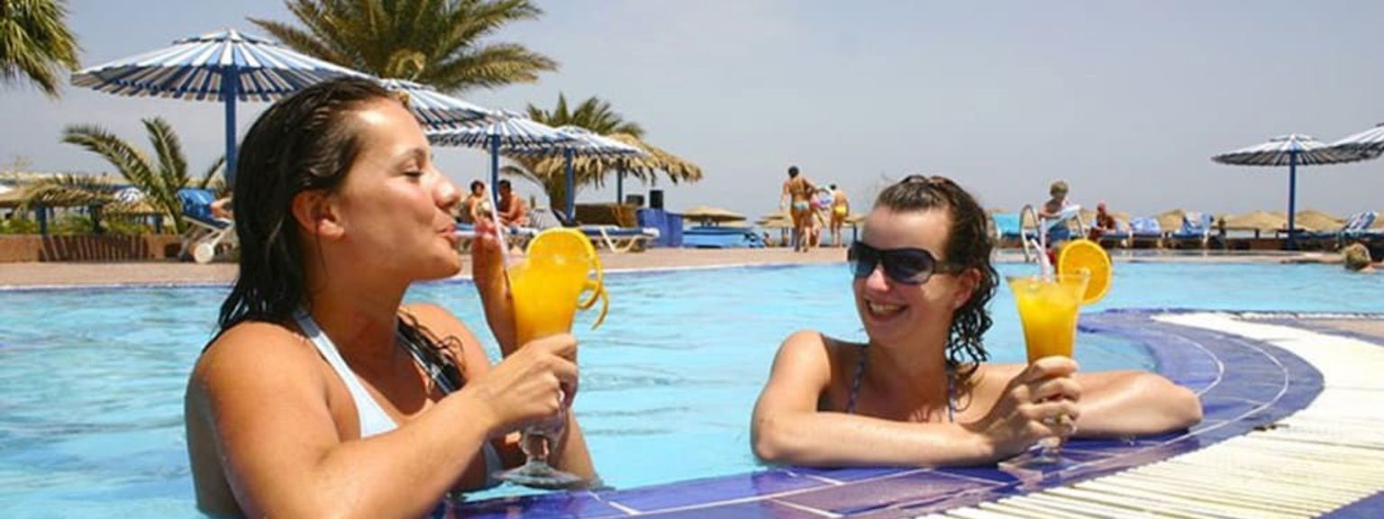 to kvinner drikker cocktails i et svømmebasseng