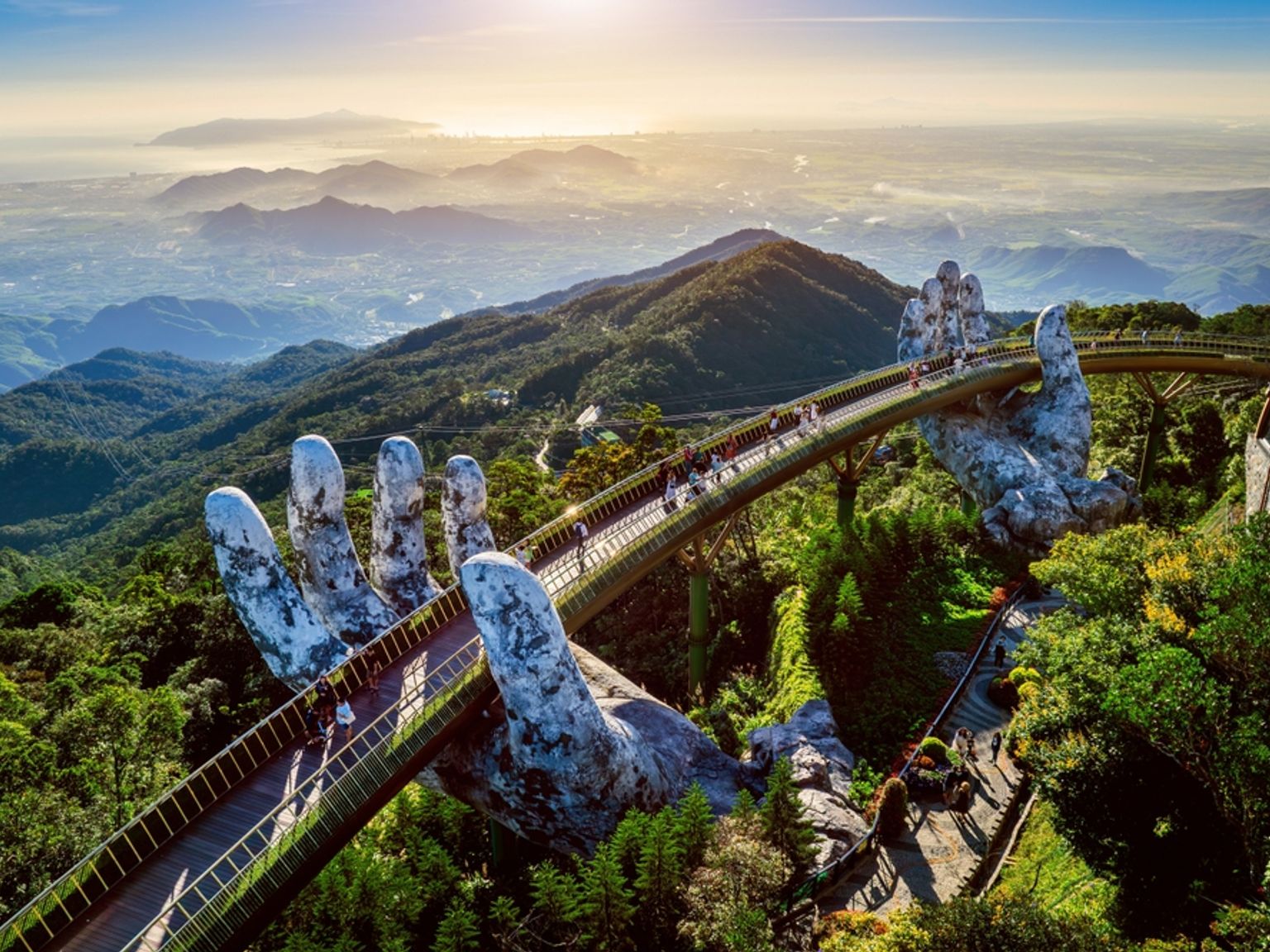 Den gyldne bro holdt af gigantiske stenhænder, der snor sig gennem frodige grønne bjerge med mennesker, der går på den. Da Nang - Vietnam