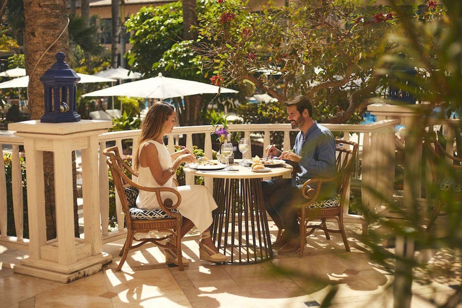 Et par spiser middag utendÞrs pÄ en solrik resortterrasse.