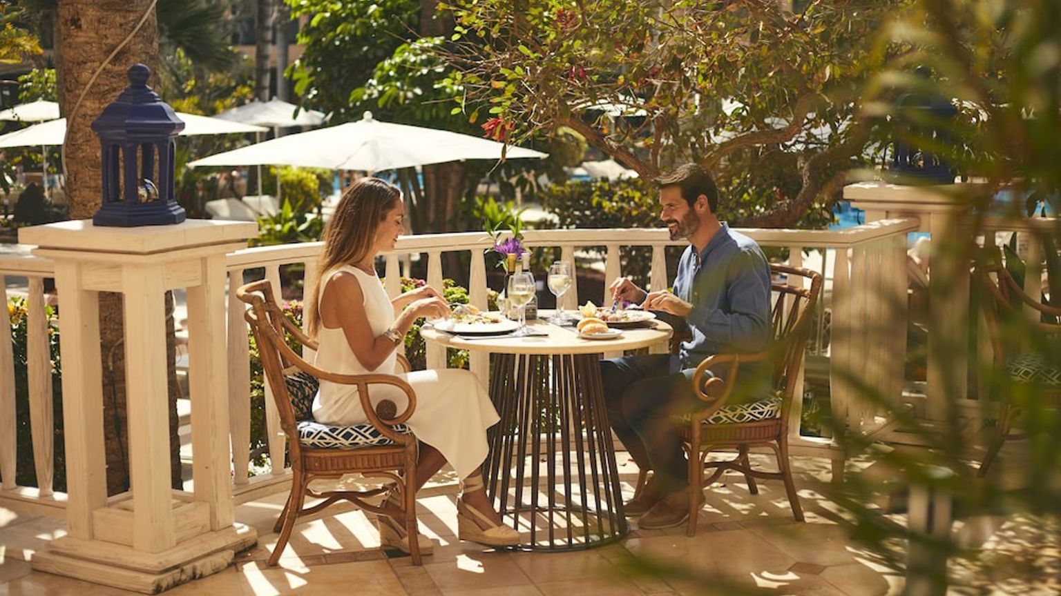 Et par spiser middag utendÞrs pÄ en solrik resortterrasse.