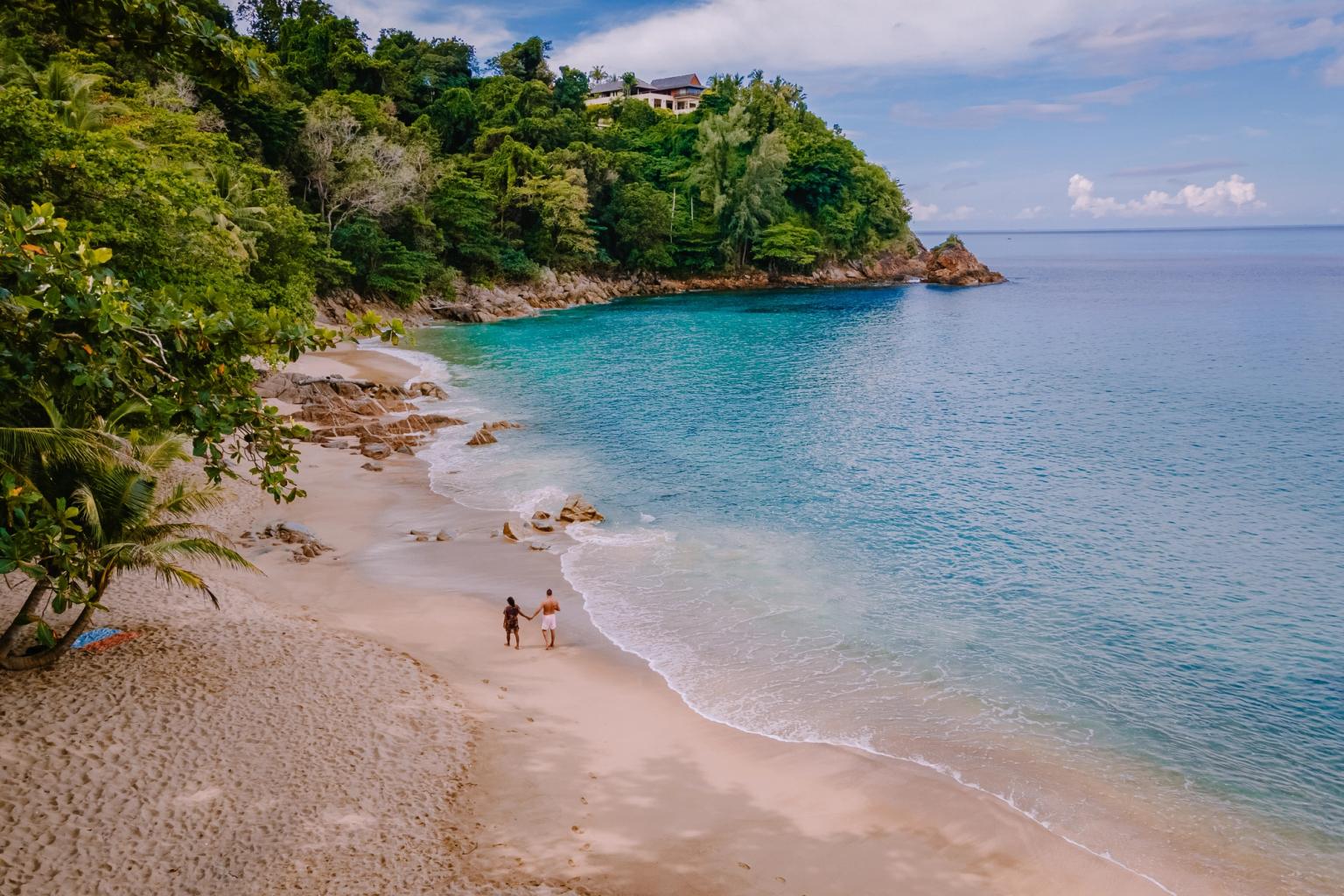 ett par går längs en sandstrand nära havet i Phuket