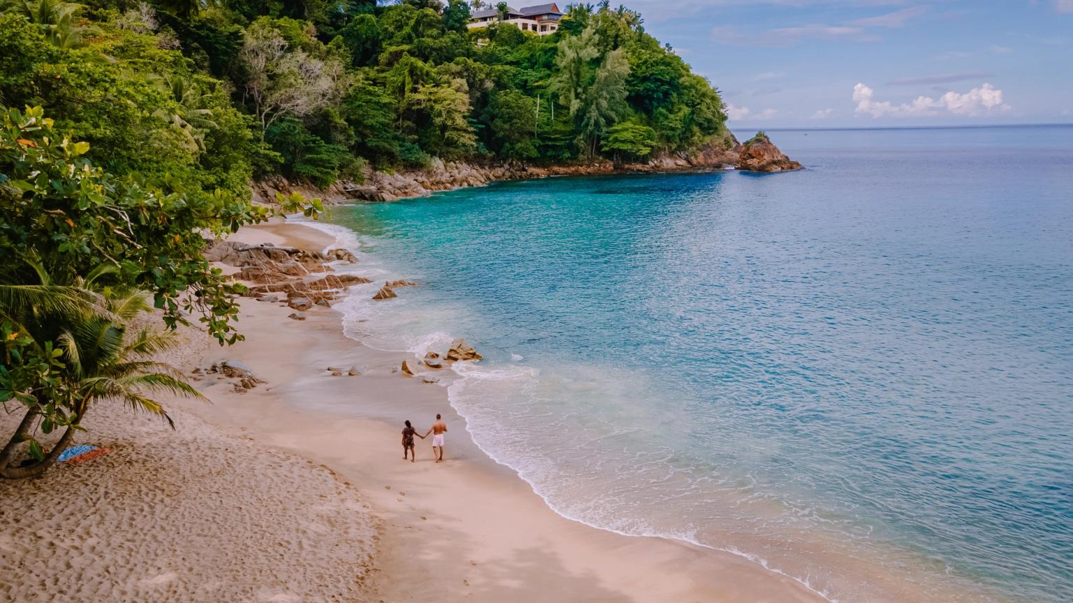 ett par går längs en sandstrand nära havet i Phuket