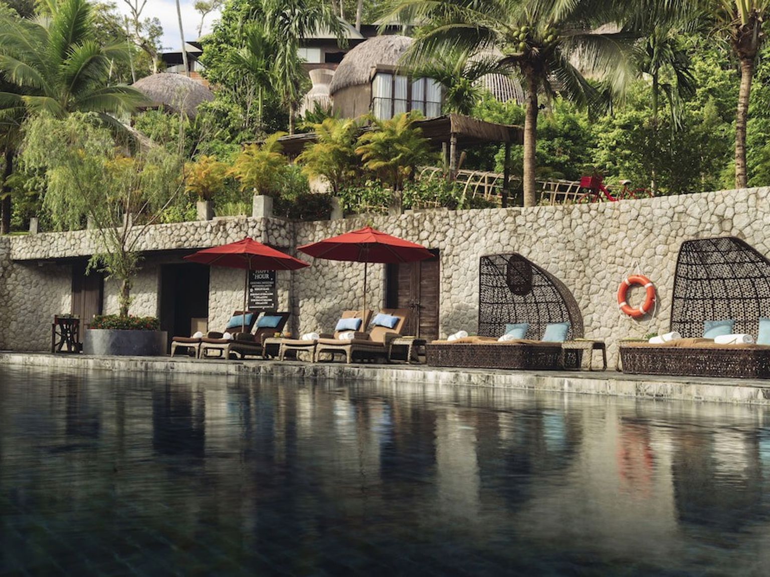 suuri uima-allas, jota ympäröivät tuolit ja aurinkovarjot lomakeskuksessa