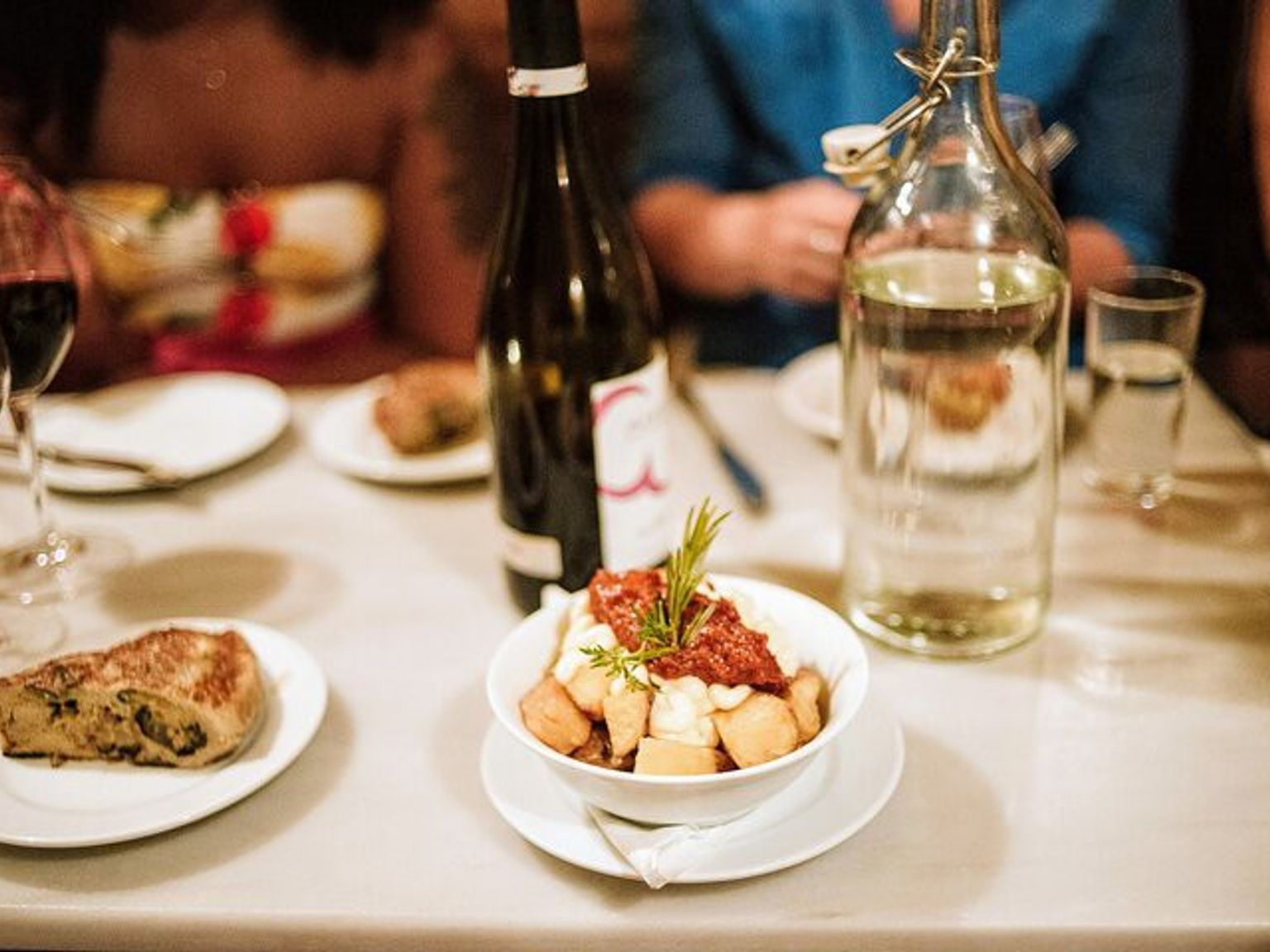 en skål med mat sitter på ett bord bredvid en flaska vin