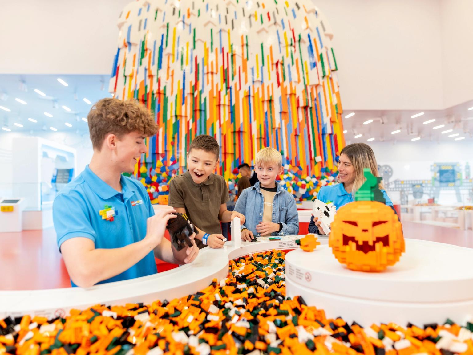 en man tar en bild av en grupp barn som leker med legobitar. Lego House, Billund