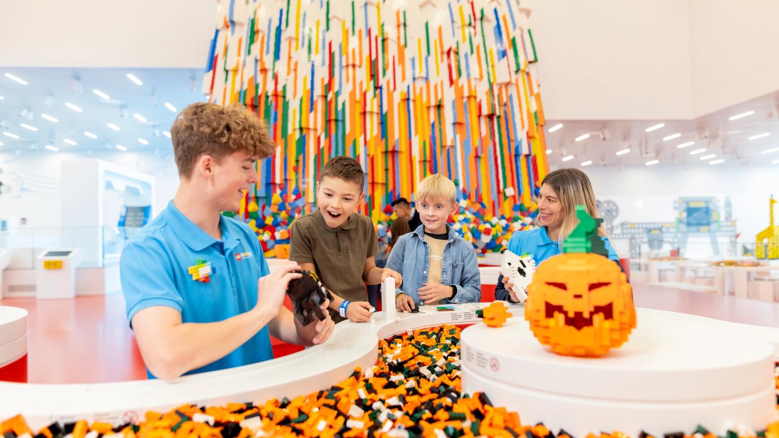 en man tar en bild av en grupp barn som leker med legobitar. Lego House, Billund