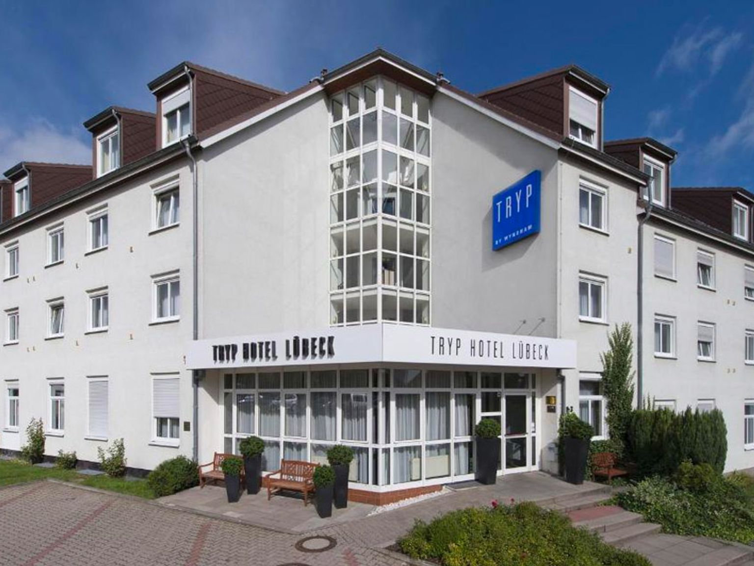 en stor vit byggnad med många fönster och en bänk framför den