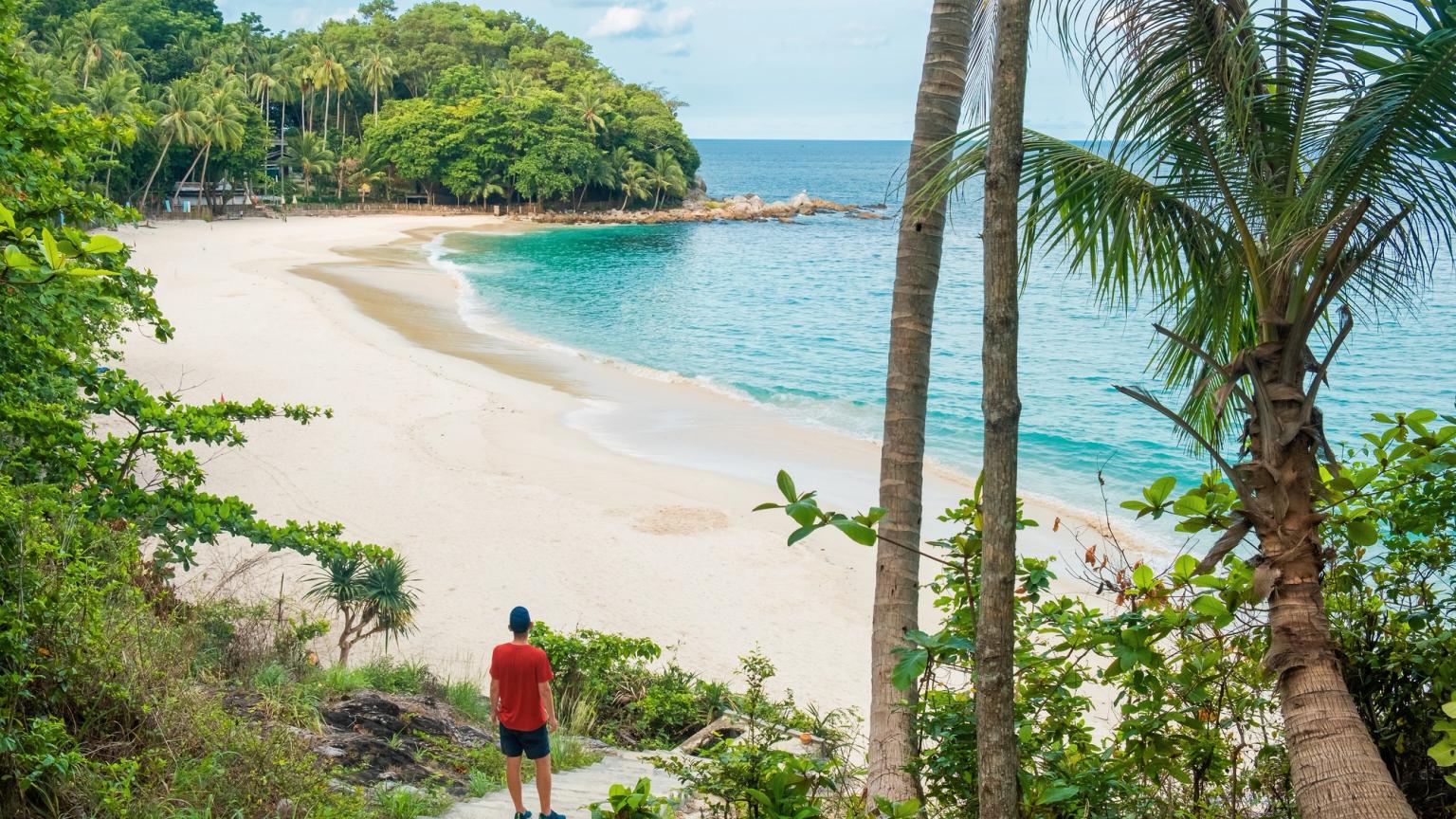 en mand står på en trappe og kigger på en strand i Phuket